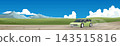 Horizontal of a light green car driving on a dusty dirt road.  Can view inside with couple consisting of a woman and a man. Open green field landscape with distant mountains under a blue sky. 143515816
