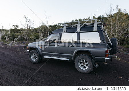 Offroad vehicle equipped with roof rack parked on volcanic terrain during expedition Offroad vehicle equipped with roof rack parked on volcanic terrain during expedition 143515833