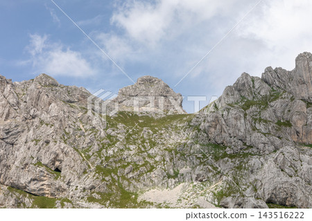 Rugged limestone mountain peaks and rocky slopes under clear blue sky Rugged limestone mountain peaks and rocky slopes under clear blue sky 143516222