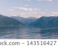 Calm water surface of Teletskoye Lake with green mountain peaks under summer sky 143516427