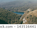 Mountain lake hidden among dense pine forest slopes on a sunny summer day 143516441