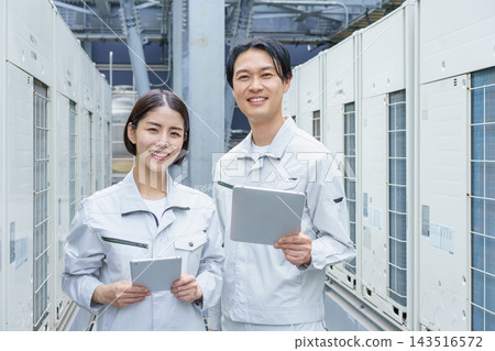 一幅描繪兩名日本年輕人(一男一女)手持平板電腦進行建築維護工作的肖像。 一幅描繪兩名日本年輕人(一男一女)手持平板電腦進行建築維護工作的肖像。 143516572