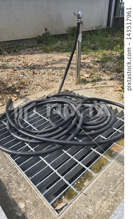 Coiled black plastic pipe on metal wire rack outdoors Coiled black plastic pipe on metal wire rack outdoors 143517961