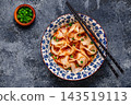 Wontons are placed in a bowl with spicy sauce. 143519113