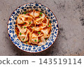 Wontons are placed in a bowl with spicy sauce. 143519114