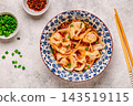 Wontons are placed in a bowl with spicy sauce. 143519115