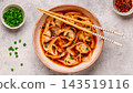 Wontons are placed in a bowl with spicy sauce. 143519116