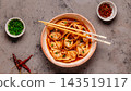 Wontons are placed in a bowl with spicy sauce. 143519117