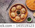 Steamed dumplings served in a bamboo basket with dipping sauce 143519123