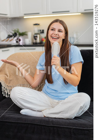 Young woman performs pop idol fantasy sings into comb as mic dances to hit song with big smile joy Young woman performs pop idol fantasy sings into comb as mic dances to hit song with big smile joy 143519276