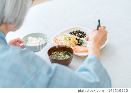 一位老年女性住院患者正在醫院食用營養均衡的飲食，以適應她的病情。 143519330