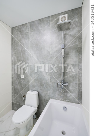 Minimal bathroom interior with bathtub, toilet and rainfall shower in gray stone finish Minimal bathroom interior with bathtub, toilet and rainfall shower in gray stone finish 143519431