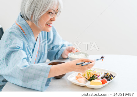 一位坐在輪椅上的老年女性住院病人正在醫院食用低熱量飲食。 一位坐在輪椅上的老年女性住院病人正在醫院食用低熱量飲食。 143519497