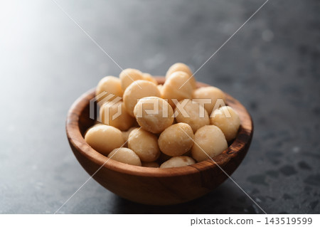 Macadamia nuts in olive wood bowl on terrazzo surface Macadamia nuts in olive wood bowl on terrazzo surface 143519599