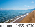 A tranquil coastline with a view of blue skies and distant mountain ranges. 143519730
