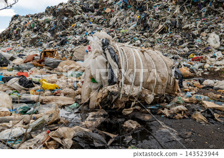 A landfill site shows a large mass of trash with plastic bags and debris spread across the area, creating an unclean environment A landfill site shows a large mass of trash with plastic bags and debris spread across the area, creating an unclean environment 143523944