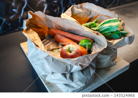 Eco Bag with Fresh Groceries. Reusable eco bag filled with fresh vegetables and fruits placed on a kitchen counter. Healthy, sustainable shopping concept. Eco Bag with Fresh Groceries. Reusable eco bag filled with fresh vegetables and fruits placed on a kitchen counter. Healthy, sustainable shopping concept. 143524968
