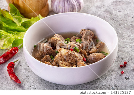 Grey stone surface bowl with tender lamb stew meat and savory broth as delicious lunch Grey stone surface bowl with tender lamb stew meat and savory broth as delicious lunch 143525127