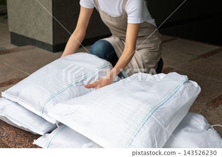 Woman setting up sandbags Woman setting up sandbags 143526230