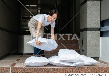 Woman setting up sandbags Woman setting up sandbags 143526231