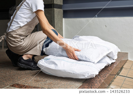 Woman setting up sandbags Woman setting up sandbags 143526233