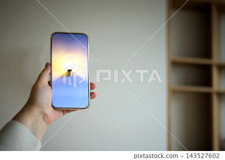 Smartphone mock up held in hand with blank gradient screen and glowing candlelike object, against softly lit wall and wooden shelving in an interior setting Smartphone mock up held in hand with blank gradient screen and glowing candlelike object, against softly lit wall and wooden shelving in an interior setting 143527602