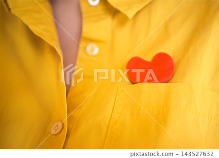 Close view of bright yellow collared shirt with visible buttons and red heart shaped object tucked into chest pocket, colorful clothing detail and symbolic accessory Close view of bright yellow collared shirt with visible buttons and red heart shaped object tucked into chest pocket, colorful clothing detail and symbolic accessory 143527632