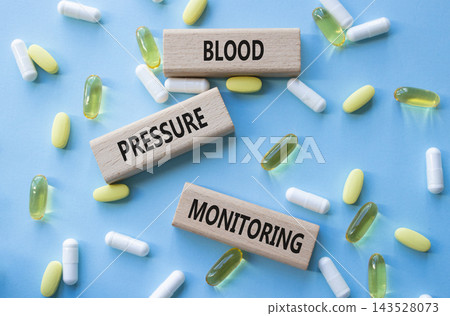 Blood Pressure Monitoring symbol. Concept words Blood Pressure Monitoring on wooden blocks. Beautiful blue background with pills. Healthcare and Blood Pressure Monitoring concept. Copy space. Blood Pressure Monitoring symbol. Concept words Blood Pressure Monitoring on wooden blocks. Beautiful blue background with pills. Healthcare and Blood Pressure Monitoring concept. Copy space. 143528073