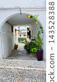 Beautiful white arched alleyway in Altea Spain old town adorned with vibrant green plants and yellow flowers, guiding visitors down sunny stone steps for a memorable family holiday trip 143528388