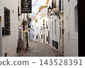 Winding narrow street lined with bright white buildings and elegant wrought iron balconies in Altea, Spain, a perfect setting for daytime family holidays and vacation 143528391