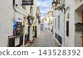 Charming cobblestone street winding through white-washed buildings in the historic old town of Altea, Spain, offering inviting restaurants for a family holiday 143528392