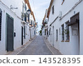 Charming cobblestone street winding uphill through Altea old town with traditional white houses and decorative streetlights under a bright sky, perfect for a Spanish holiday exploration 143528395