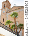 Historic Altea church bell tower and facade with lush palm trees under a bright sky, a beautiful Spanish travel destination for family holidays 143528403