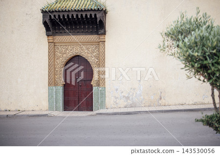 Ornate wooden door with intricate carvings and colorful tiles, set against a textured wall, showcasing architectural beauty and cultural heritage in a serene urban environment Ornate wooden door with intricate carvings and colorful tiles, set against a textured wall, showcasing architectural beauty and cultural heritage in a serene urban environment 143530056