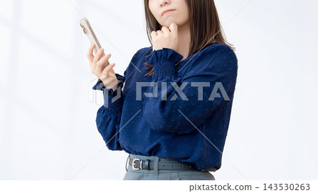A woman thinking with a smartphone A woman thinking with a smartphone 143530263