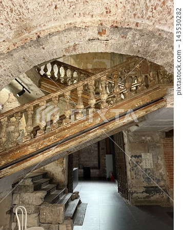 Historic stone staircase beneath weathered arched ceiling in restored European building interior 143530282