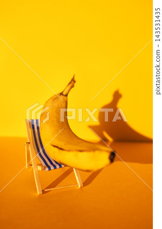 Banana placed on a small beach chair against a bright yellow background, casting a shadow that adds depth to the playful and whimsical composition Banana placed on a small beach chair against a bright yellow background, casting a shadow that adds depth to the playful and whimsical composition 143531435