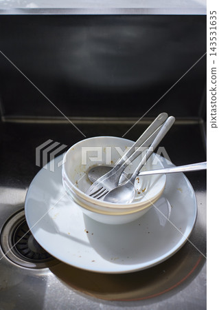 Dirty tableware and metal utensils remain in sink after eating Dirty tableware and metal utensils remain in sink after eating 143531635
