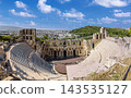 Odeon of Herodes Atticus ancient theater ruins with Athens cityscape in background under blue sky 143535127