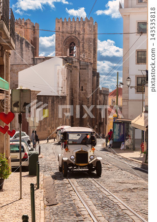 Vintage Tourist Car on Cobblestone Street Near Lisbon Cathedral, Portugal Vintage Tourist Car on Cobblestone Street Near Lisbon Cathedral, Portugal 143535818