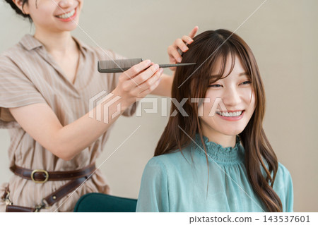 一位留著長髮的年輕女子正在美髮沙龍做頭髮。 一位留著長髮的年輕女子正在美髮沙龍做頭髮。 143537601