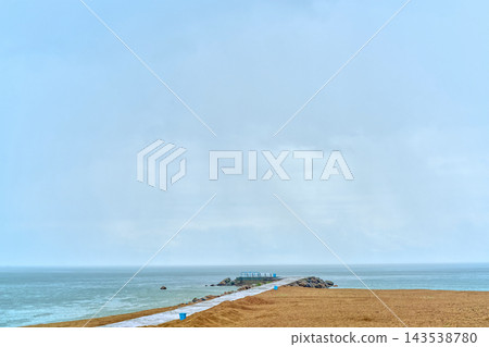 Beach sand management with jetty structure at overcast coastal location Beach sand management with jetty structure at overcast coastal location 143538780