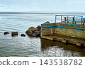 Coastal pier structure with seating overlooking calm water, overcast conditions 143538782