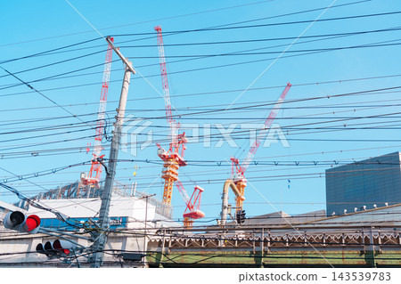 在城市景觀中，架空電線和建築起重機交錯重疊。 143539783