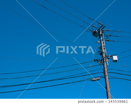 藍天下聳立著電線桿和輸電線路:這是支撐電力供應的電氣基礎設施。 藍天下聳立著電線桿和輸電線路:這是支撐電力供應的電氣基礎設施。 143539861