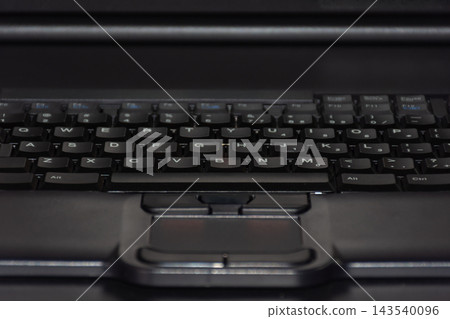 Close up of black laptop keyboard visible letter keys integrated touchpad soft low light highlighting modern computer hardware digital technology everyday office equipment Close up of black laptop keyboard visible letter keys integrated touchpad soft low light highlighting modern computer hardware digital technology everyday office equipment 143540096