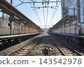 A Japanese train station platform and tracks extending straight down the center. 143542978