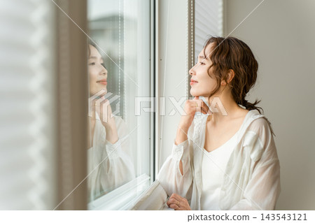 一位女士在客廳的窗邊放鬆身心,凝視著窗外。這是她生命中難得的寧靜時刻。 一位女士在客廳的窗邊放鬆身心,凝視著窗外。這是她生命中難得的寧靜時刻。 143543121