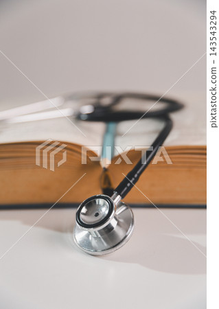 Stethoscope placed in front of an open book with pencil, representing medical education, healthcare learning, academic study and preparation for a professional medical career. 143543294