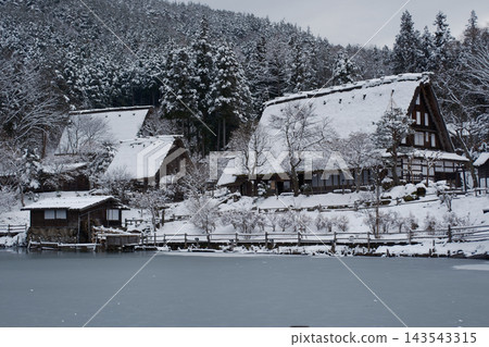 一座被雪覆蓋的茅草屋和一個冬日池塘 143543315
